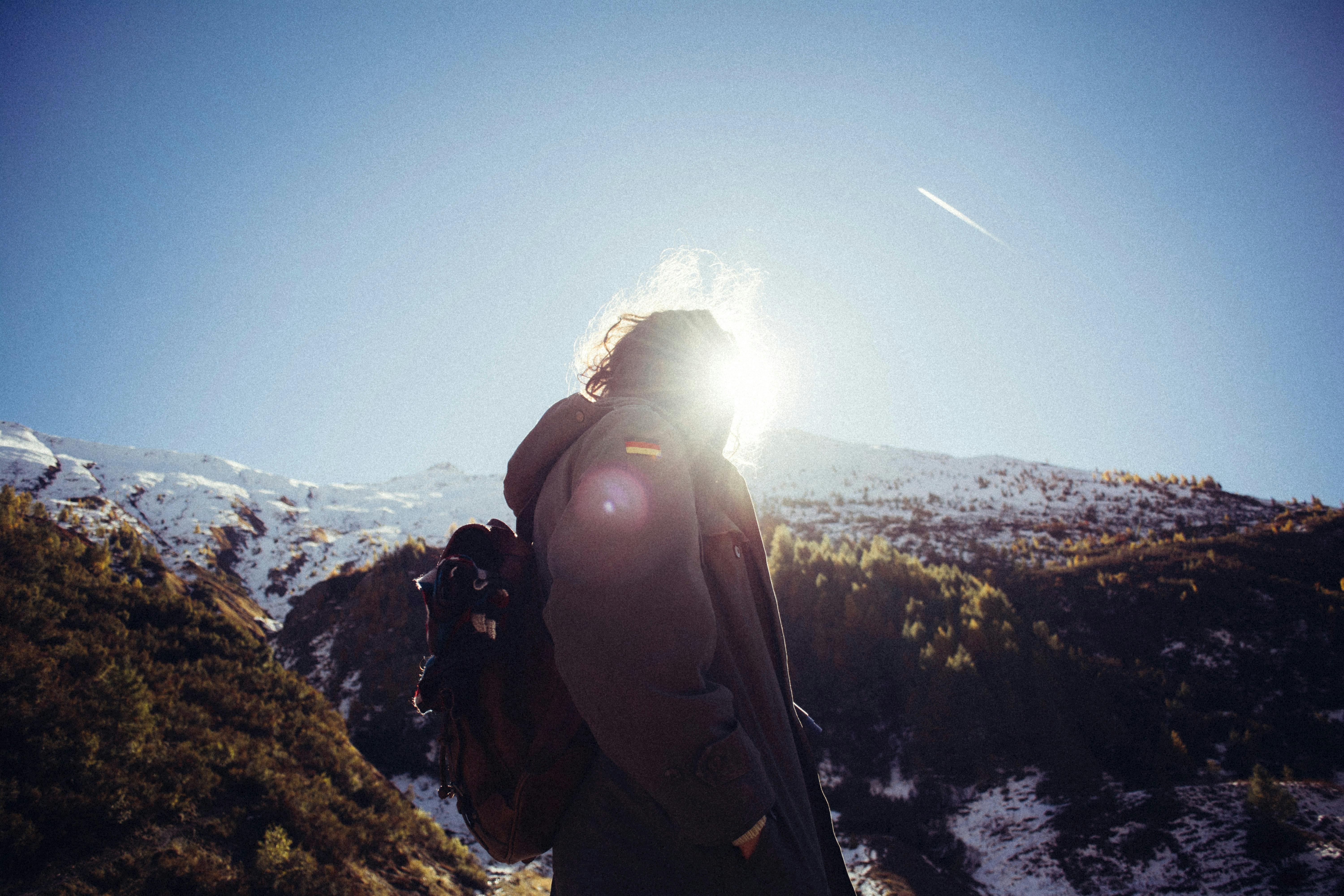 Hiker on a high-altitude ridge with intense sunlight and clear sky
