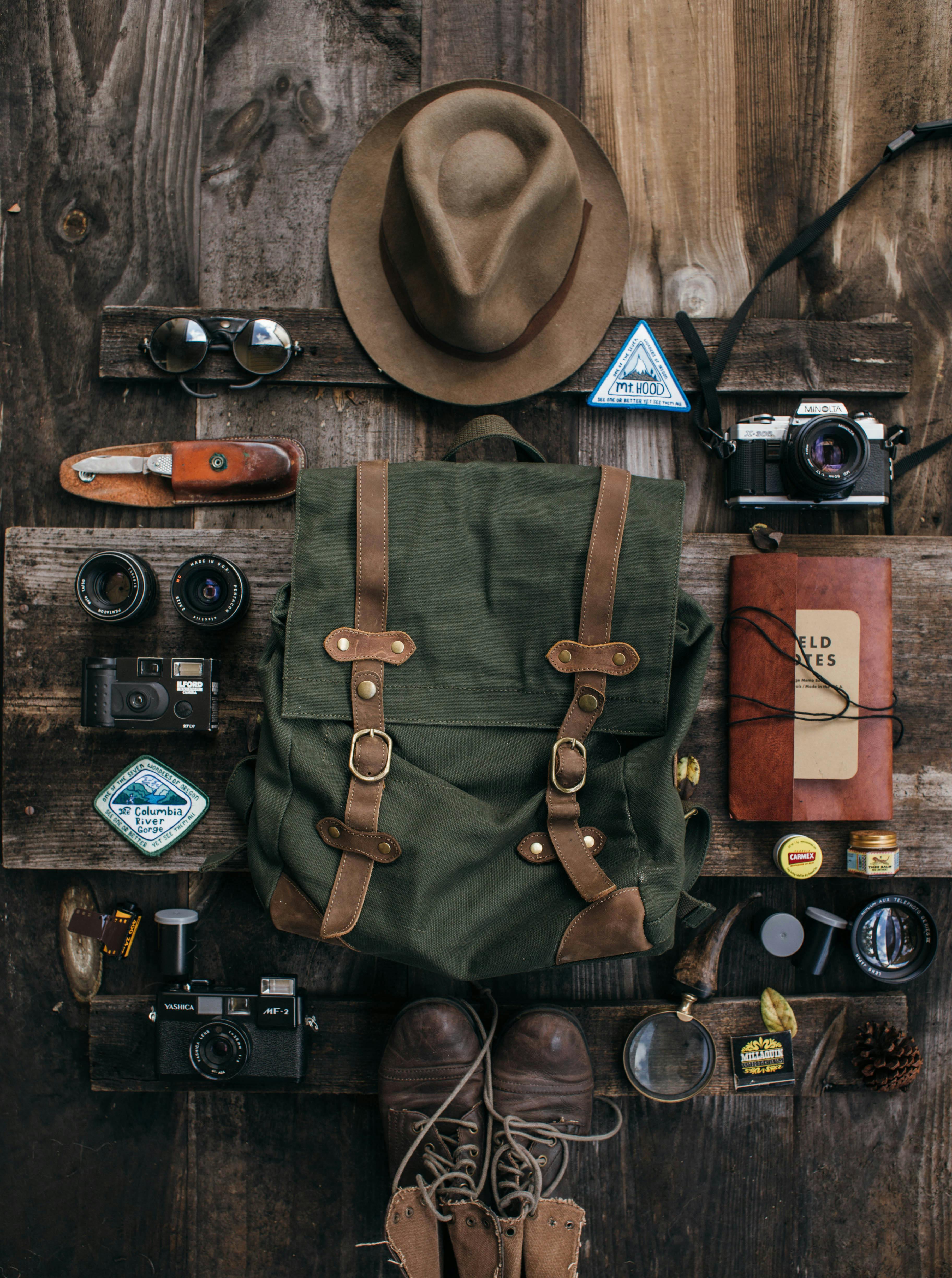 Hiking gear laid out on a wooden surface including sunglasses, water bottle, and trail map