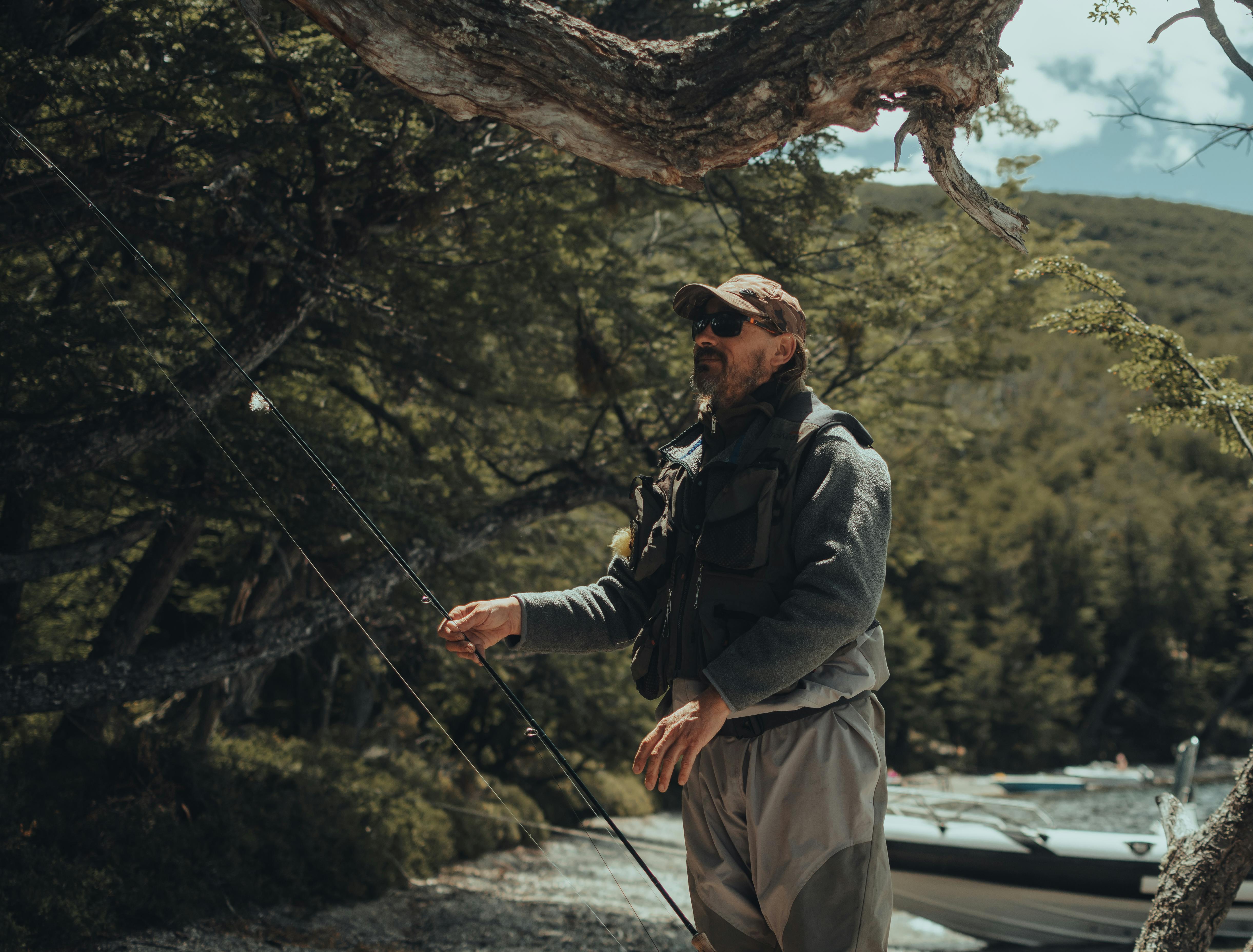 Angler on a river bank wearing sunglasses, water surface visible